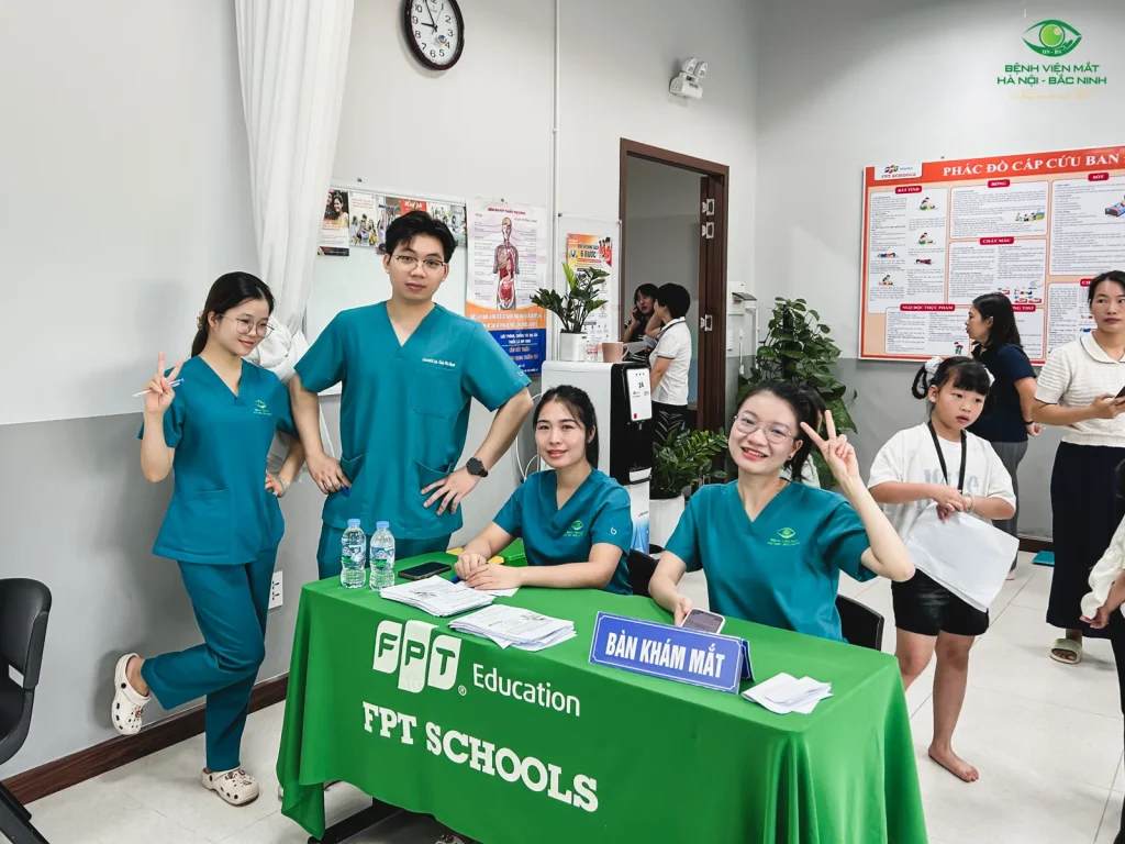 Đội ngũ bệnh viện bên bàn khám mắt mang nhận diện FPT Schools.