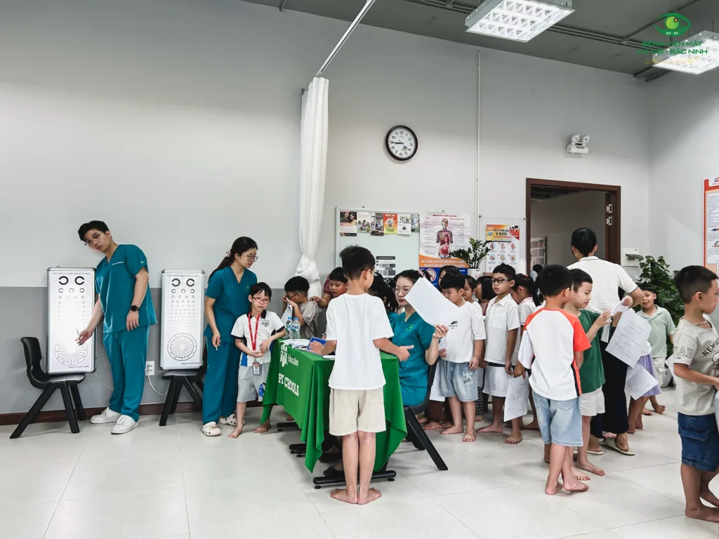Nhân viên y tế bên bảng thị lực và học sinh tại khu vực khám mắt FPT Bắc Giang.