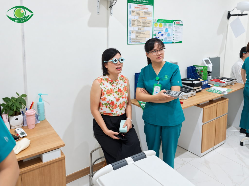 Người phụ nữ đeo kính thử ngồi cạnh nhân viên y tế đang cầm bộ điều khiển.
