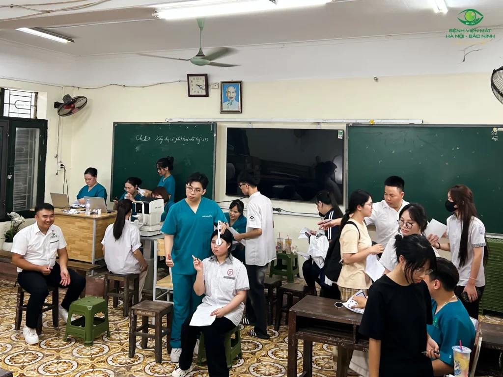 Nhân viên y tế hướng dẫn học sinh kiểm tra thị lực từng mắt trong phòng học.